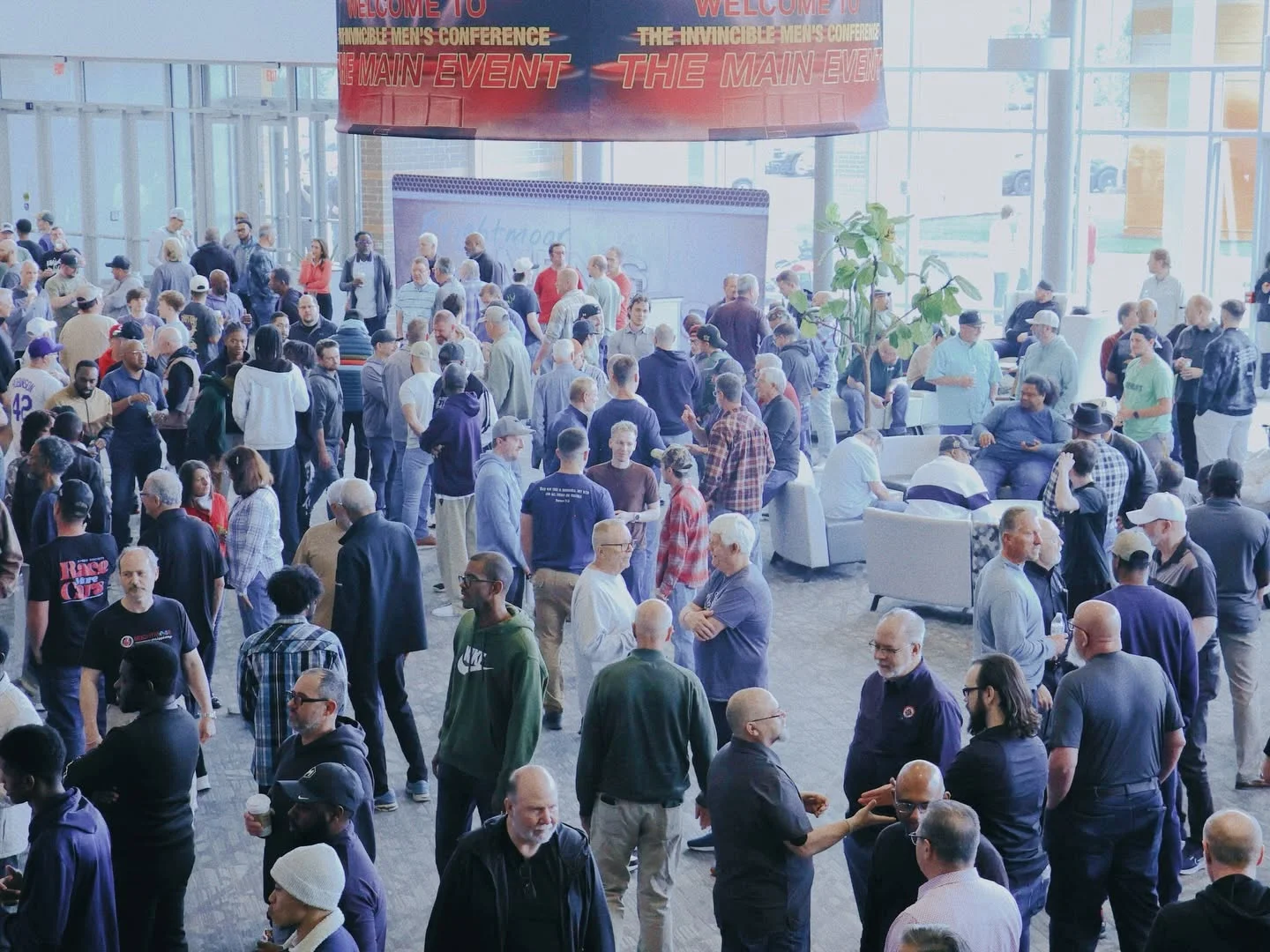 Men connecting in the bright, busy Brightmoor lobby during Invincible 2026