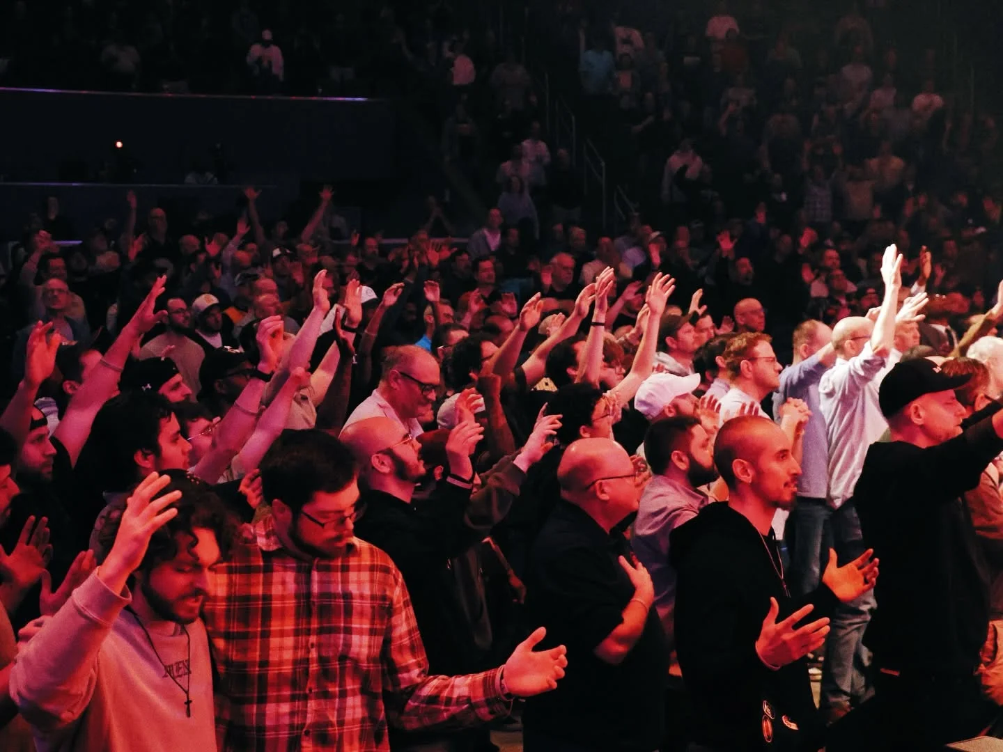 Men with hands raised in worship at Invincible 2026